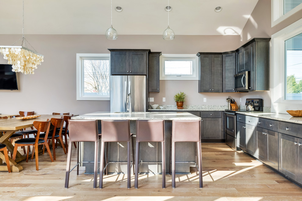 Inspiration for a mid-sized transitional l-shaped light wood floor and brown floor open concept kitchen remodel with an undermount sink, shaker cabinets, gray cabinets, granite countertops, stainless steel appliances, an island and gray countertops