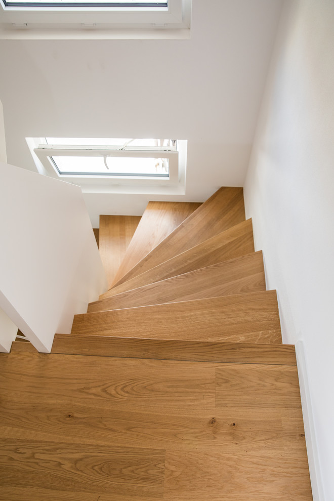 Cette image montre un escalier courbe design avec des marches en bois et un garde-corps en bois.
