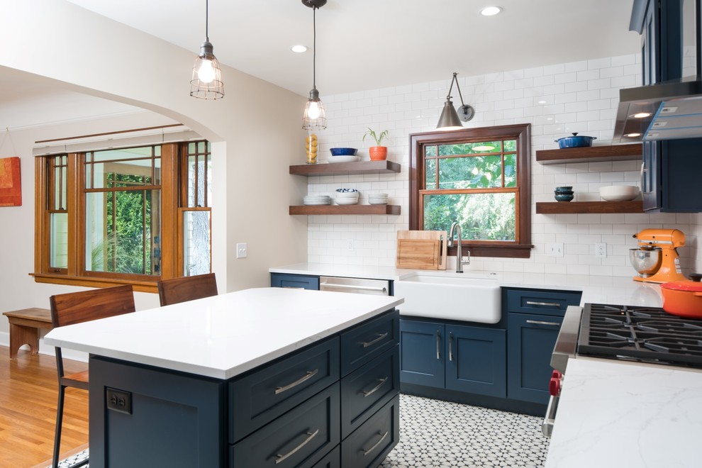 Inspiration for a small eclectic l-shaped eat-in kitchen in Seattle with a farmhouse sink, raised-panel cabinets, blue cabinets, quartzite benchtops, white splashback, ceramic splashback, stainless steel appliances, cement tiles, with island and black floor.