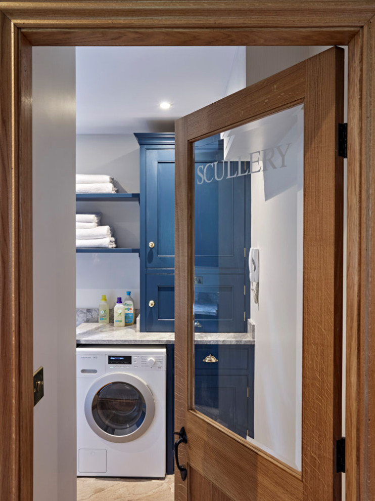 Photo of a mid-sized l-shaped dedicated laundry room in Other with a farmhouse sink, beaded inset cabinets, blue cabinets, quartzite benchtops, white walls, an integrated washer and dryer and grey benchtop.