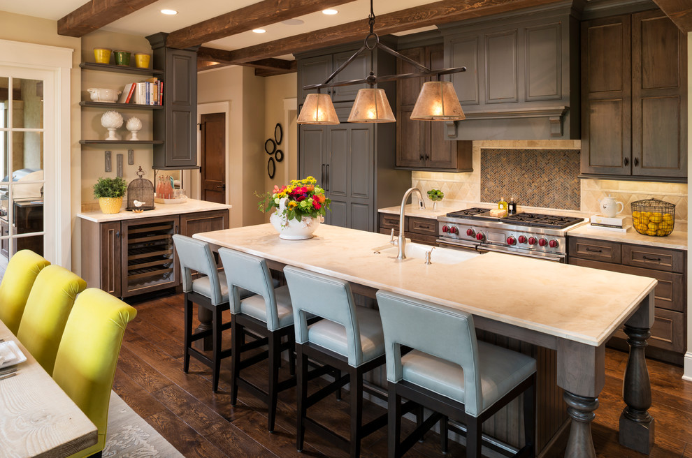 Photo of a large traditional l-shaped open plan kitchen in Minneapolis with a farmhouse sink, beaded inset cabinets, limestone benchtops, beige splashback, stone tile splashback, with island, dark wood cabinets, stainless steel appliances, dark hardwood floors and brown floor.