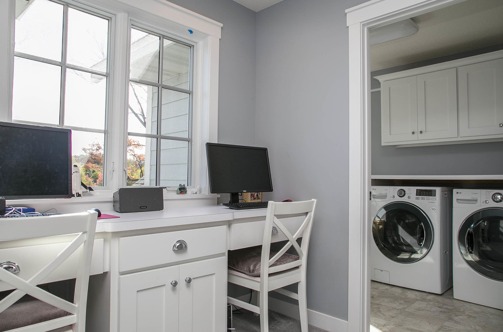 Photo of a transitional l-shaped utility room in Minneapolis with shaker cabinets, white cabinets, laminate benchtops, grey walls, carpet and a side-by-side washer and dryer.
