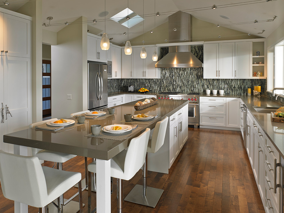 This is an example of a large transitional u-shaped open plan kitchen in Seattle with an undermount sink, shaker cabinets, white cabinets, quartz benchtops, multi-coloured splashback, mosaic tile splashback, stainless steel appliances, dark hardwood floors, with island and brown floor.