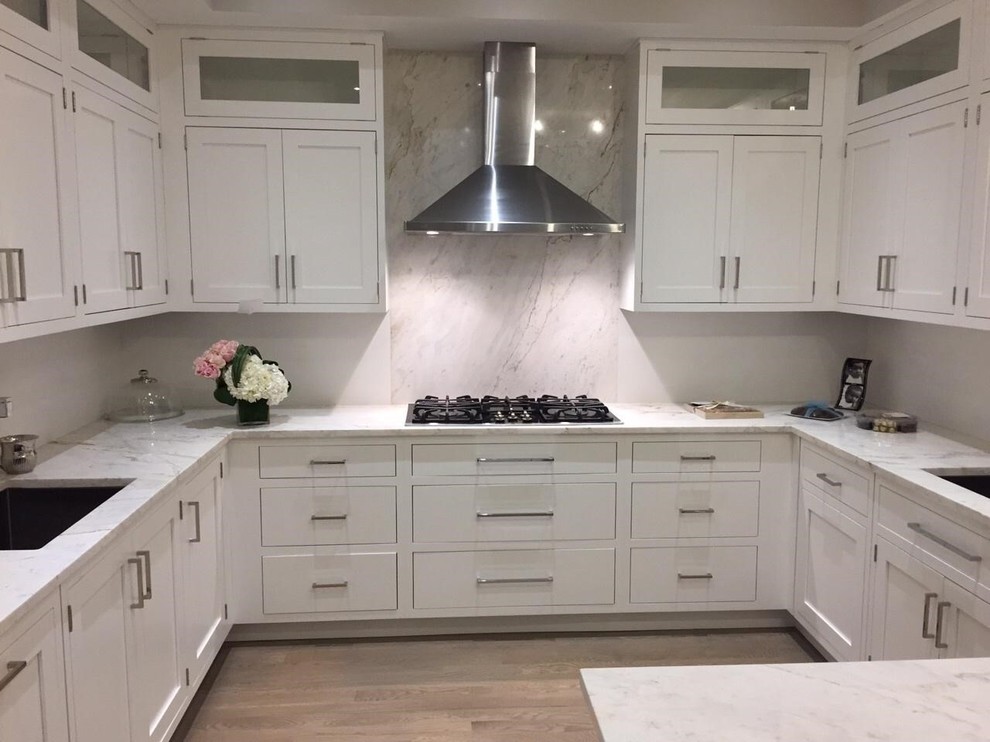 Design ideas for a mid-sized transitional u-shaped separate kitchen in New York with a peninsula, an undermount sink, shaker cabinets, white cabinets, marble benchtops, white splashback, stainless steel appliances, medium hardwood floors, marble splashback and brown floor.