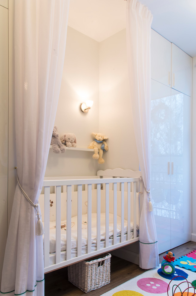 Photo of a contemporary gender-neutral nursery in Saint Petersburg with white walls and dark hardwood floors.