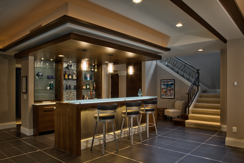 Inspiration for a large contemporary single-wall seated home bar in Minneapolis with flat-panel cabinets, brown cabinets, glass benchtops, blue splashback, glass tile splashback, porcelain floors, grey floor and blue benchtop.