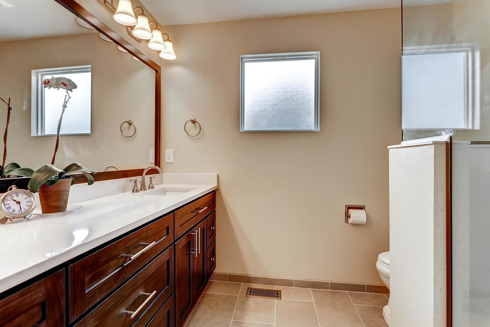 Inspiration for a small transitional master cement tile ceramic tile doorless shower remodel in Denver with shaker cabinets, dark wood cabinets, a one-piece toilet, beige walls, an undermount sink and quartz countertops