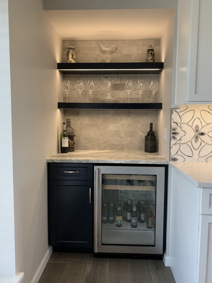 This is an example of a transitional l-shaped home bar in Other with an undermount sink, recessed-panel cabinets, white cabinets, granite benchtops, multi-coloured splashback, ceramic splashback and multi-coloured benchtop.