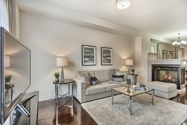 Mid-sized transitional open concept family room in Toronto with beige walls, dark hardwood floors, a freestanding tv, a two-sided fireplace and a tile fireplace surround.