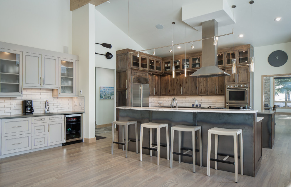 Example of a huge transitional l-shaped light wood floor and brown floor open concept kitchen design in Denver with an undermount sink, shaker cabinets, medium tone wood cabinets, quartz countertops, white backsplash, subway tile backsplash, stainless steel appliances, two islands and multicolored countertops