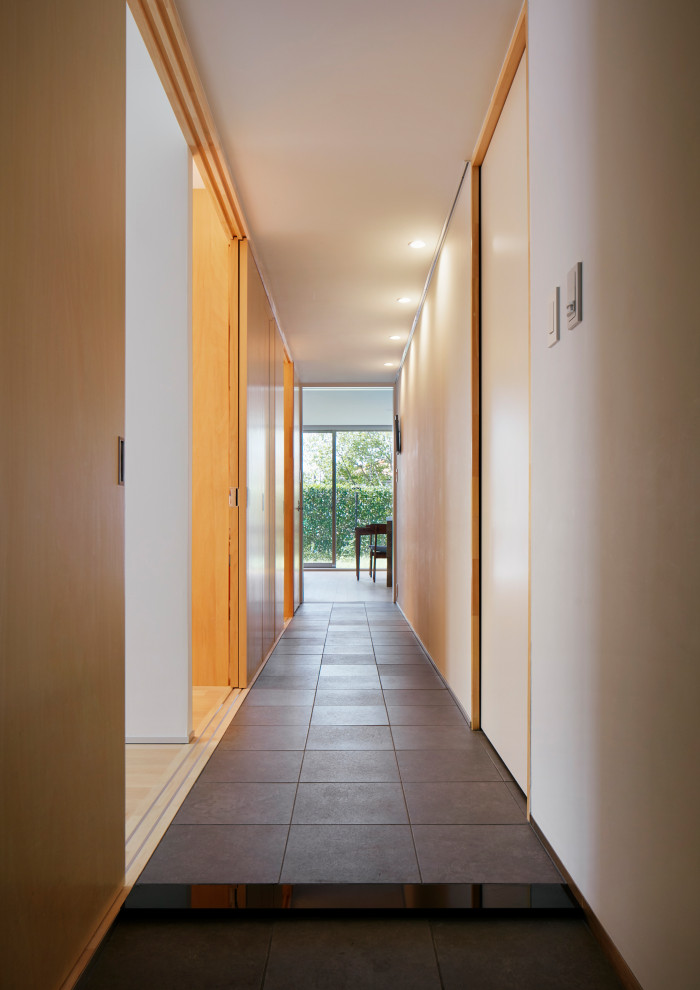 Cette image montre un couloir de taille moyenne avec un mur blanc, un sol en carrelage de porcelaine, un sol gris, un plafond en lambris de bois et du lambris de bois.