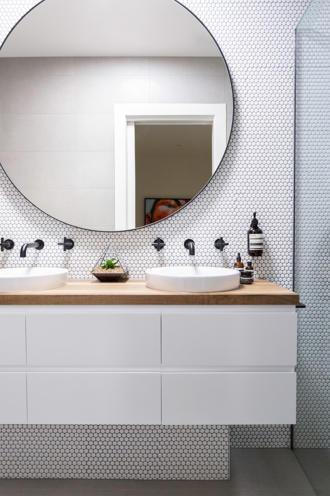 Design ideas for a mid-sized contemporary 3/4 bathroom in Melbourne with white cabinets, a vessel sink, wood benchtops, flat-panel cabinets, a curbless shower, white tile, mosaic tile, white walls, grey floor and brown benchtops.