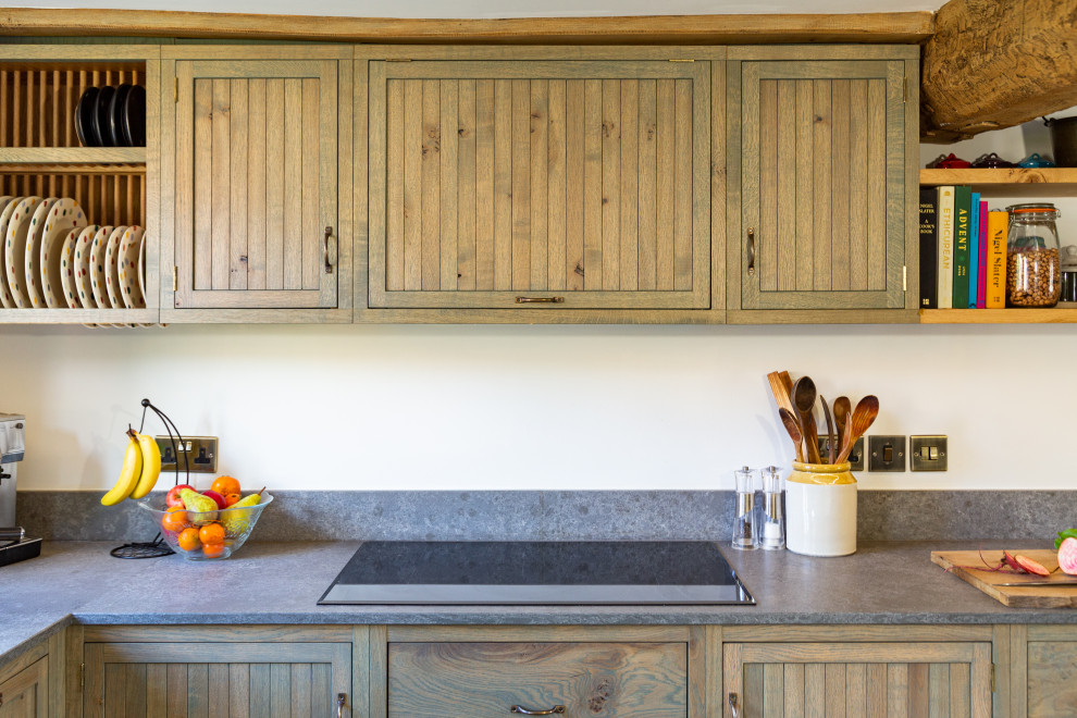 Photo of a mid-sized country galley eat-in kitchen in West Midlands with a farmhouse sink, shaker cabinets, green cabinets, quartzite benchtops, grey splashback, engineered quartz splashback, panelled appliances, slate floors, no island, grey floor, grey benchtop and exposed beam.