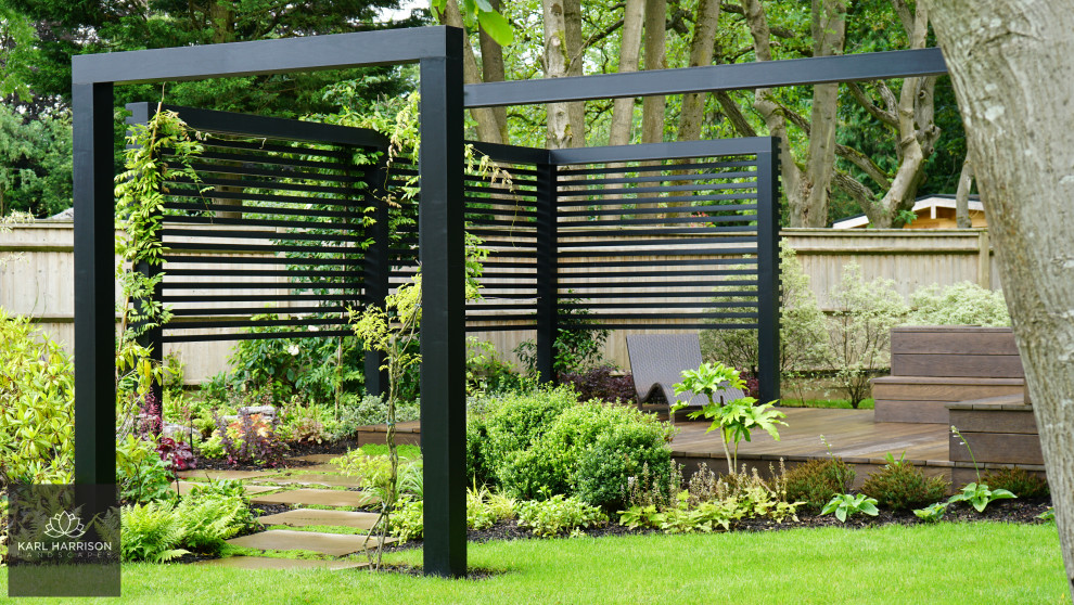 Foto di un grande giardino minimalista esposto in pieno sole dietro casa in estate con pedane e recinzione in legno