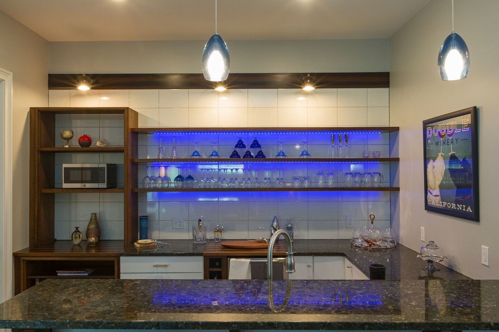 This is an example of a large modern u-shaped seated home bar in Other with an undermount sink, open cabinets, dark wood cabinets, granite benchtops, white splashback, porcelain splashback, medium hardwood floors and brown floor.
