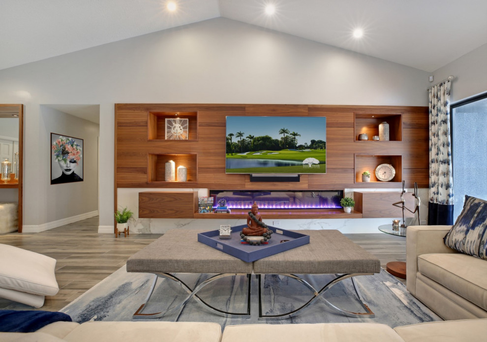 Mid-sized contemporary open concept living room in Miami with grey walls, porcelain floors, a standard fireplace, a tile fireplace surround, a built-in media wall, grey floor, vaulted and wood walls.