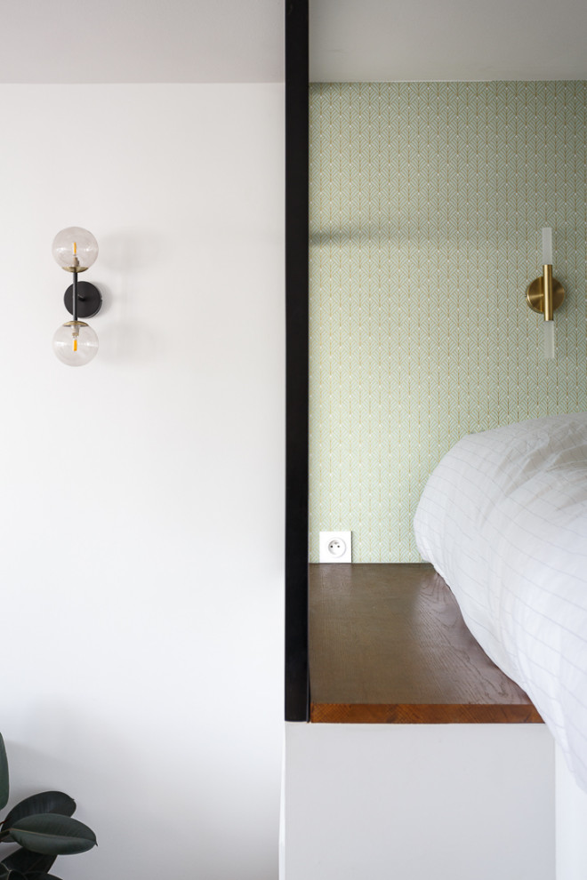 Esempio di una piccola camera da letto stile loft con pareti bianche, pavimento in legno massello medio, nessun camino, pavimento marrone e carta da parati