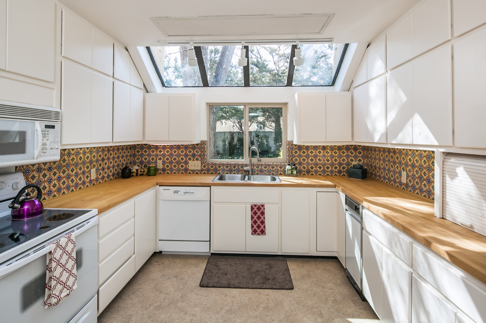 Inspiration for a mid-sized midcentury u-shaped separate kitchen in Albuquerque with a drop-in sink, flat-panel cabinets, white cabinets, wood benchtops, multi-coloured splashback, ceramic splashback, white appliances, linoleum floors and no island.