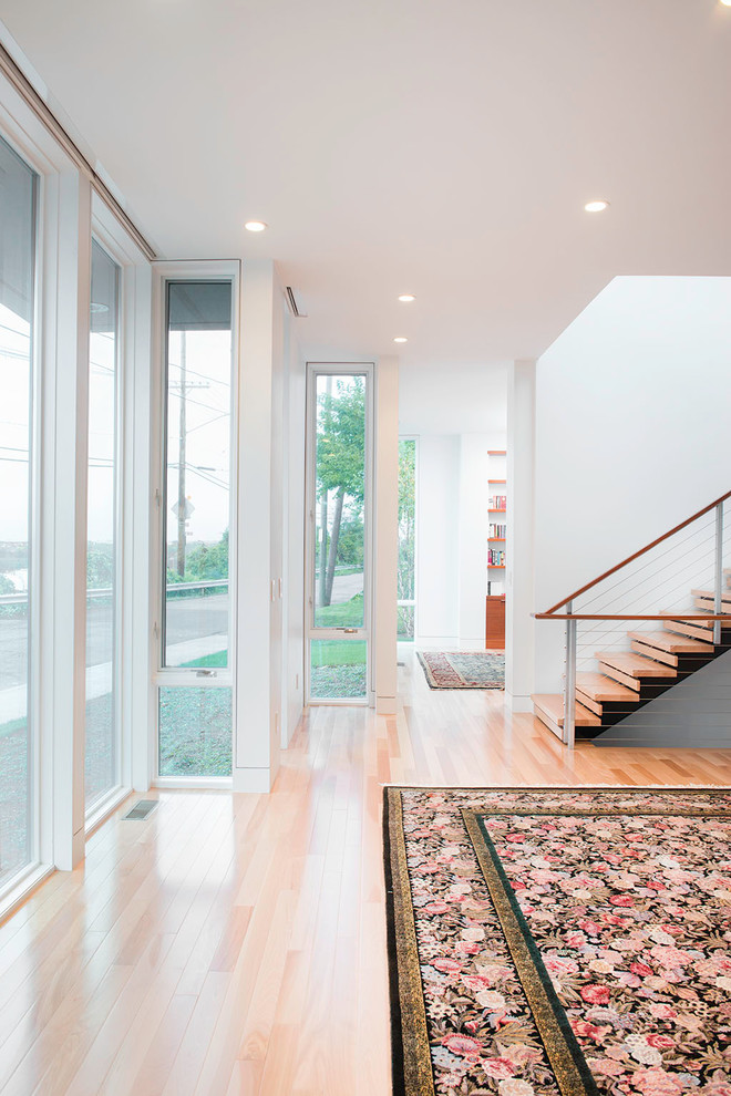 Design ideas for a mid-sized contemporary hallway in Cleveland with white walls, light hardwood floors and beige floor.