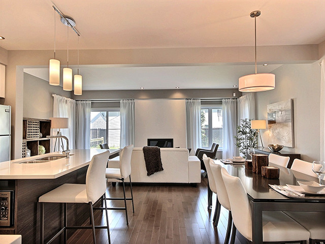 This is an example of a small contemporary l-shaped eat-in kitchen in Ottawa with an undermount sink, flat-panel cabinets, white cabinets, white splashback, ceramic splashback, stainless steel appliances, with island, quartzite benchtops, medium hardwood floors and brown floor.