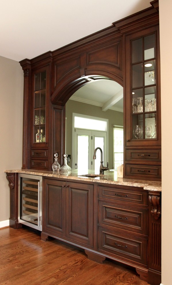 Mid-sized traditional single-wall wet bar with an undermount sink, beaded inset cabinets, dark wood cabinets, granite benchtops and medium hardwood floors.