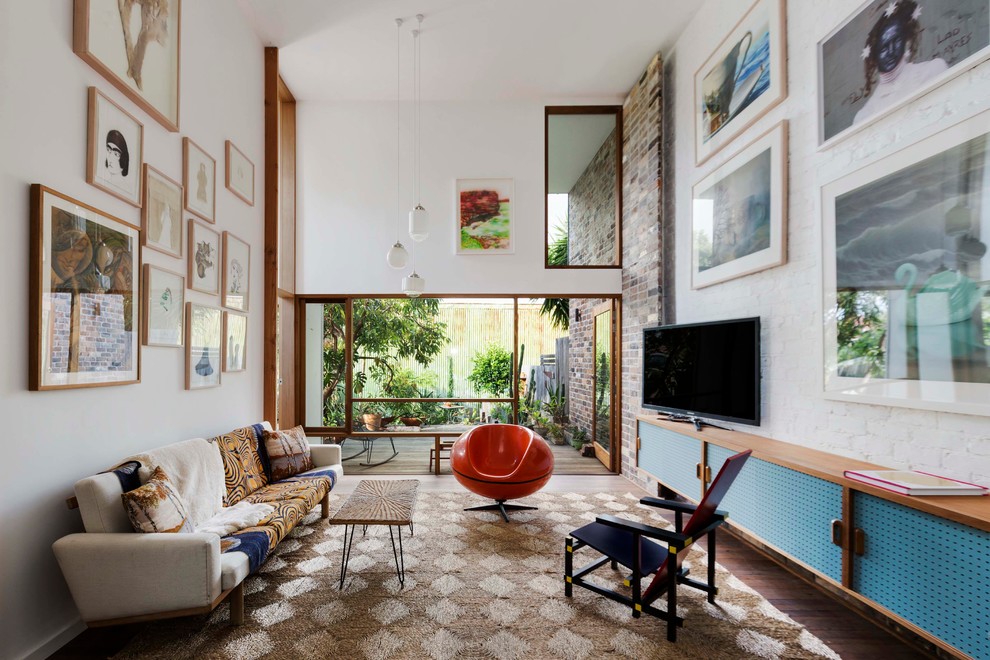 Photo of a mid-sized eclectic open concept living room in Sydney with white walls, dark hardwood floors and a freestanding tv.