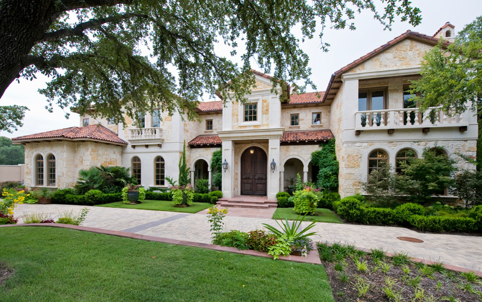 Inspiration for a large mediterranean two-storey beige exterior in Dallas with stone veneer and a hip roof.