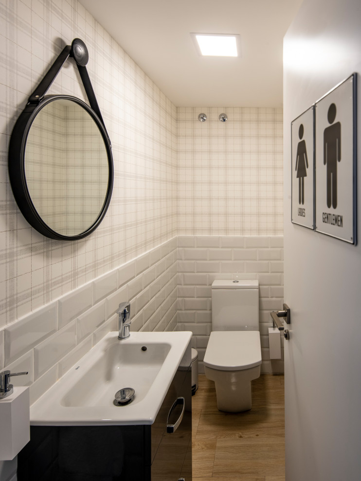 Moderne Gästetoilette mit weißer Wandfarbe und braunem Holzboden in Sonstige
