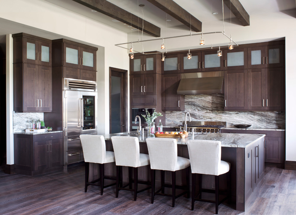 Photo of a country kitchen in Denver with an undermount sink, shaker cabinets, dark wood cabinets, stainless steel appliances, dark hardwood floors, with island and brown floor.