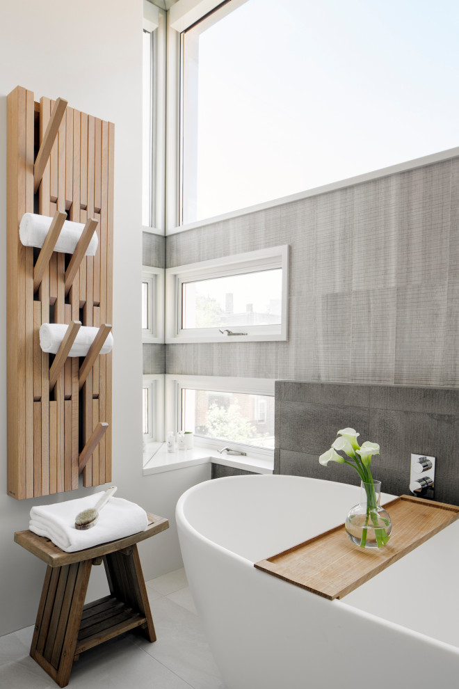 This is an example of a mid-sized modern master bathroom in Boston with flat-panel cabinets, light wood cabinets, a japanese tub, an open shower, a one-piece toilet, gray tile, cement tile, white walls, concrete floors, a console sink, quartzite benchtops, grey floor, a hinged shower door and white benchtops.