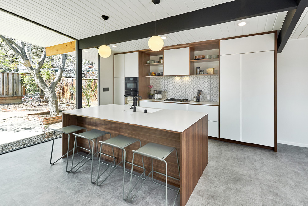 Contemporary galley open plan kitchen in San Francisco with an integrated sink, linoleum floors, flat-panel cabinets, white cabinets, white splashback, panelled appliances, with island, grey floor and white benchtop.