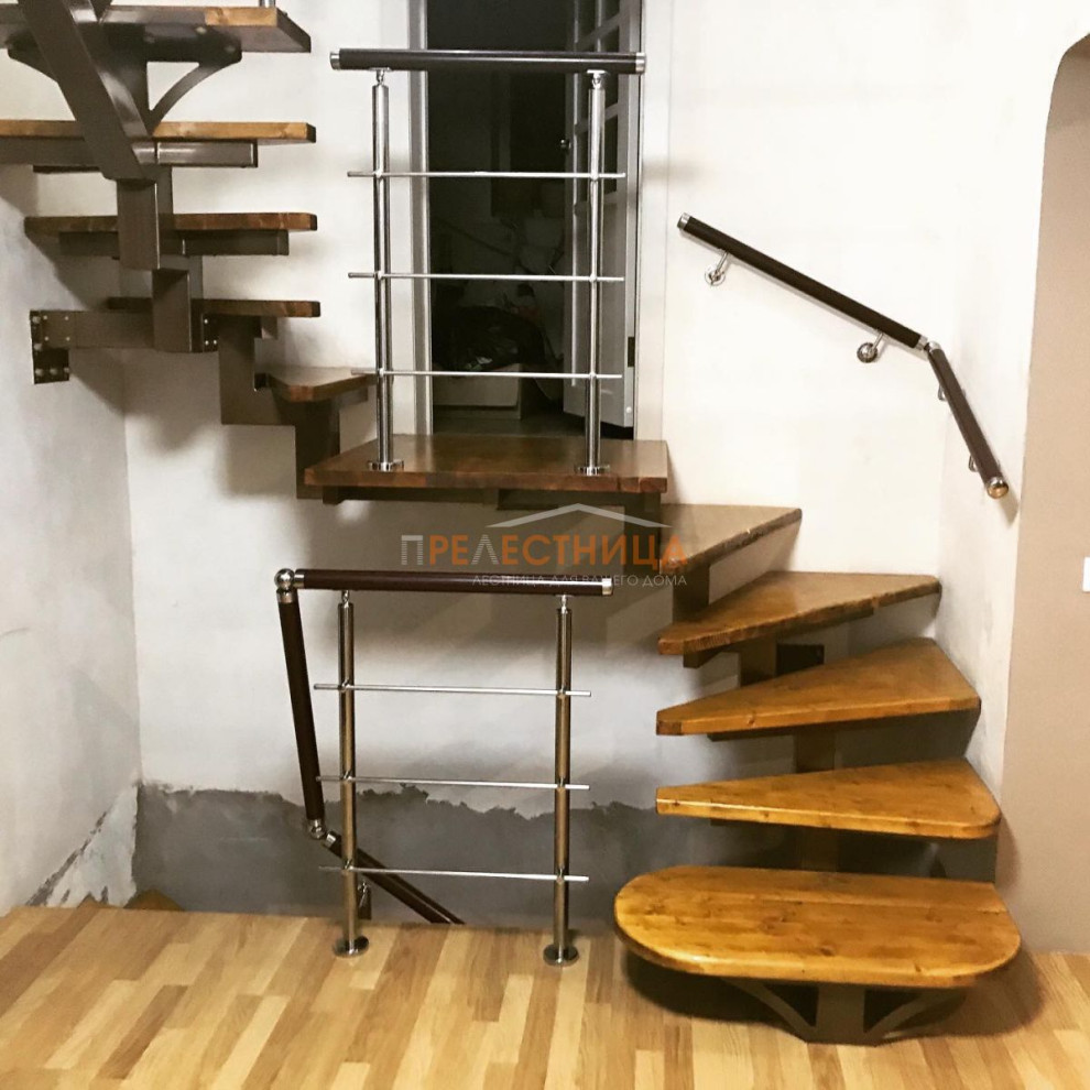 На фото: п-образная металлическая лестница среднего размера с крашенными деревянными ступенями и перилами из смешанных материалов с