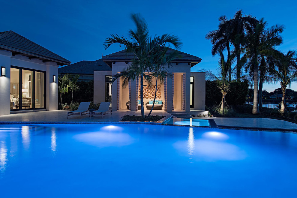 Example of a large transitional backyard stone and custom-shaped infinity pool house design in Miami