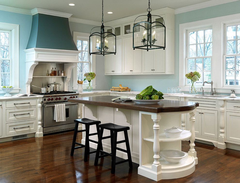 Inspiration for a large timeless u-shaped dark wood floor eat-in kitchen remodel with an undermount sink, recessed-panel cabinets, white cabinets, wood countertops, blue walls, stainless steel appliances and a peninsula