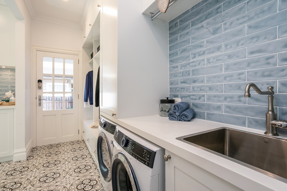 Design ideas for a mid-sized single-wall dedicated laundry room in Sydney with shaker cabinets, white cabinets, quartz benchtops, subway tile splashback, blue walls, porcelain floors, a side-by-side washer and dryer and white benchtop.