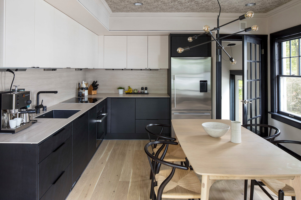 Inspiration for a small modern l-shaped eat-in kitchen in Minneapolis with a single-bowl sink, flat-panel cabinets, black cabinets, solid surface benchtops, beige splashback, ceramic splashback, stainless steel appliances, medium hardwood floors, no island and brown floor.