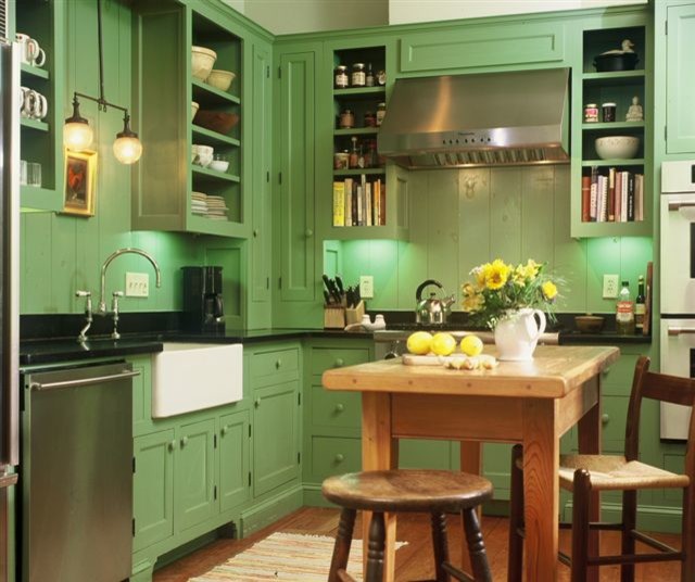 This is an example of a mid-sized country l-shaped separate kitchen in Atlanta with a farmhouse sink, recessed-panel cabinets, green cabinets, solid surface benchtops, green splashback, timber splashback, stainless steel appliances, medium hardwood floors, with island and brown floor.