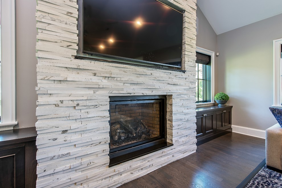Photo of a large country open concept family room in Chicago with beige walls, medium hardwood floors, a standard fireplace, a stone fireplace surround, a wall-mounted tv and brown floor.