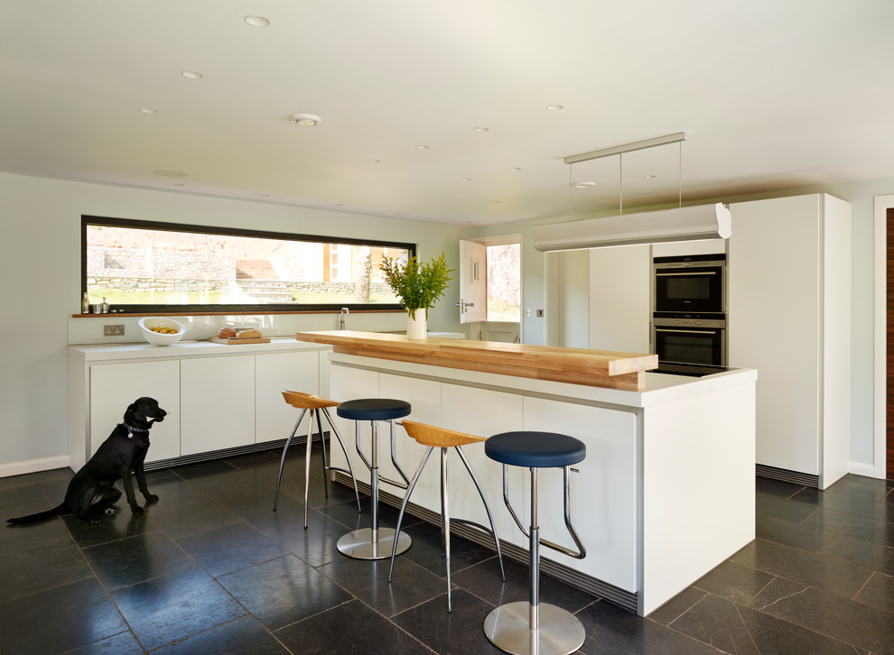 Photo of a kitchen in Devon with white cabinets, laminate benchtops and slate floors.