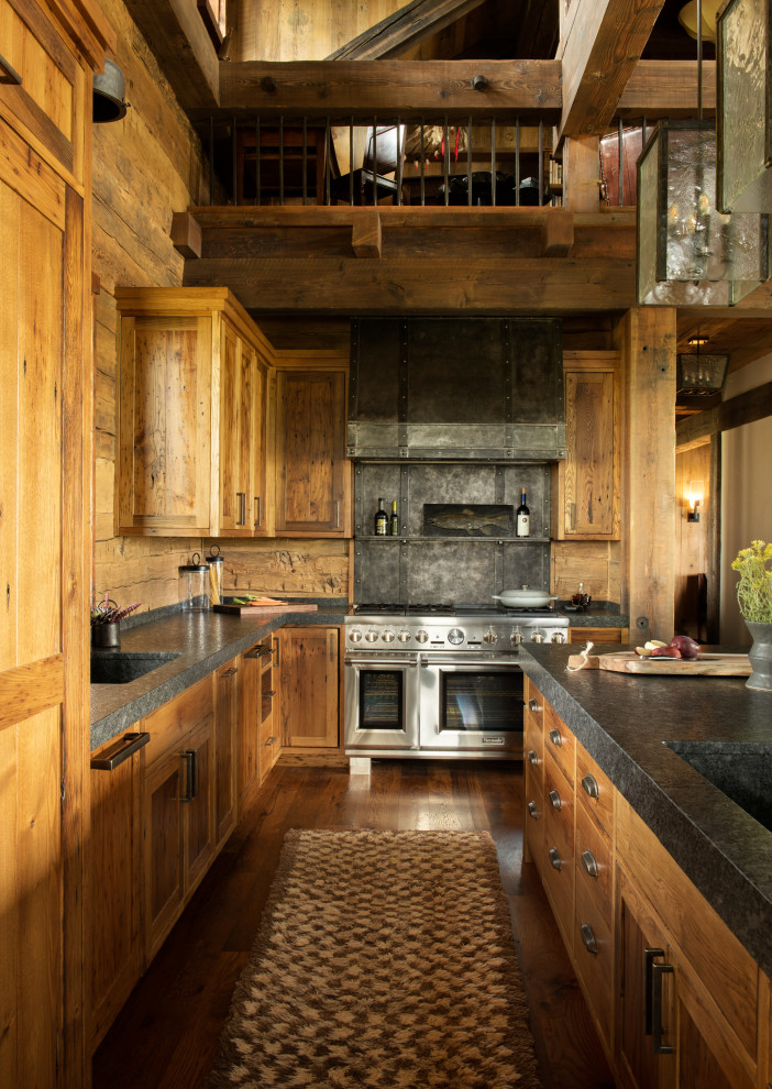 Inredning av ett amerikanskt stort svart svart kök, med en integrerad diskho, luckor med infälld panel, skåp i mellenmörkt trä, stänkskydd i trä, rostfria vitvaror, mörkt trägolv och en köksö
