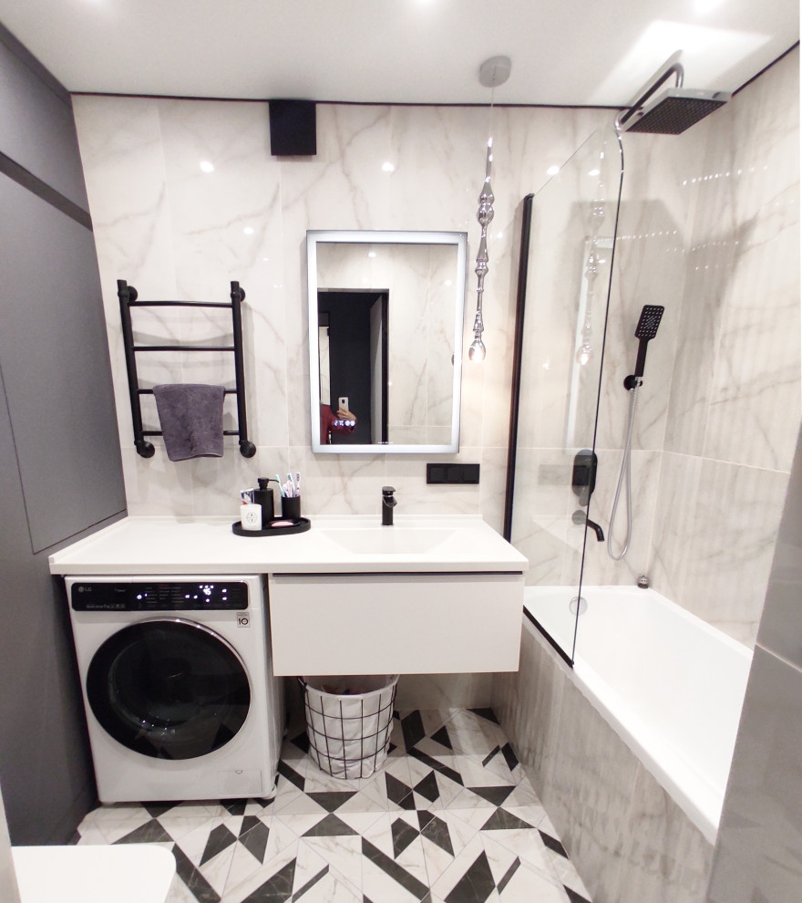 Small contemporary grey and white ensuite bathroom in Other with flat-panel cabinets, grey cabinets, a submerged bath, a wall mounted toilet, white tiles, marble tiles, white walls, porcelain flooring, an integrated sink, solid surface worktops, black floors, white worktops, a laundry area, a single sink and a floating vanity unit.