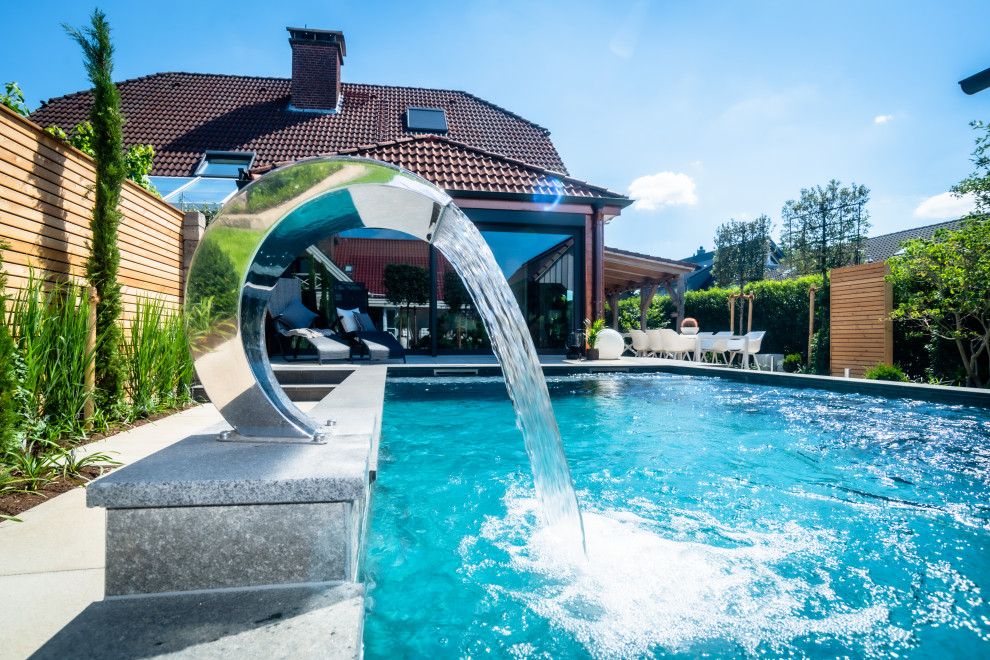 Halbschattiger Moderner Garten mit Wasserspiel und Natursteinplatten in Sonstige