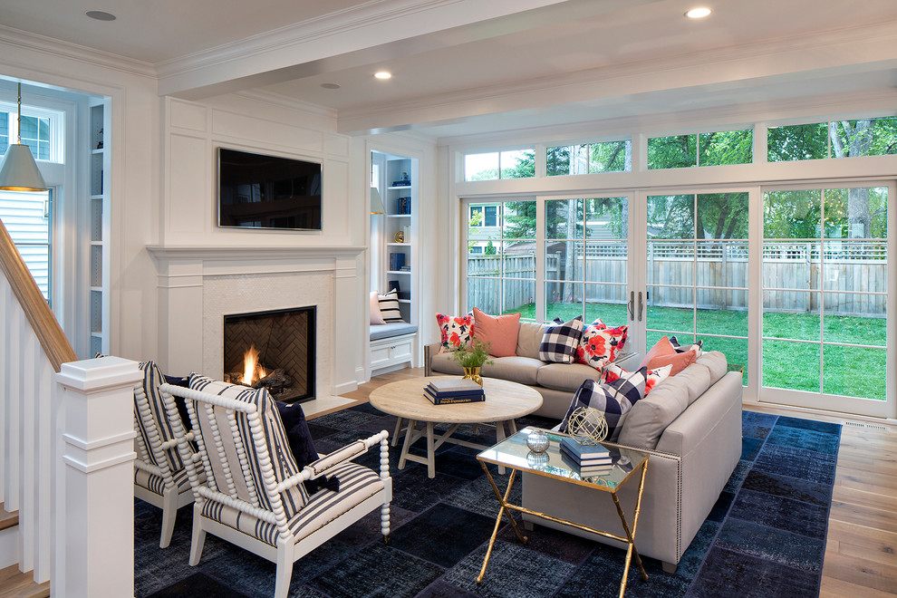 This is an example of a mid-sized transitional open concept family room in Minneapolis with white walls, light hardwood floors, a standard fireplace, a tile fireplace surround and a wall-mounted tv.