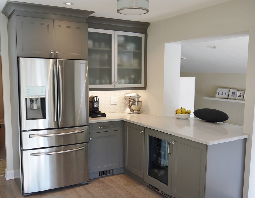Enclosed kitchen - mid-sized transitional l-shaped light wood floor enclosed kitchen idea in Toronto with an undermount sink, recessed-panel cabinets, gray cabinets, quartz countertops, white backsplash, porcelain backsplash, stainless steel appliances and an island