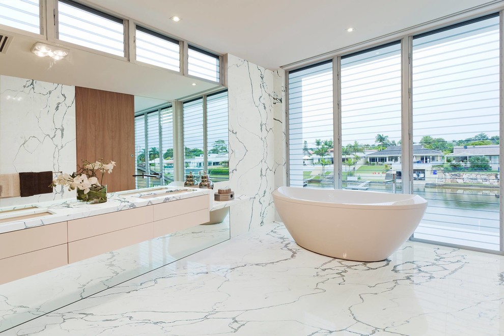Contemporary master bathroom in New York with flat-panel cabinets, white cabinets, a freestanding tub, grey walls, an undermount sink and white floor.