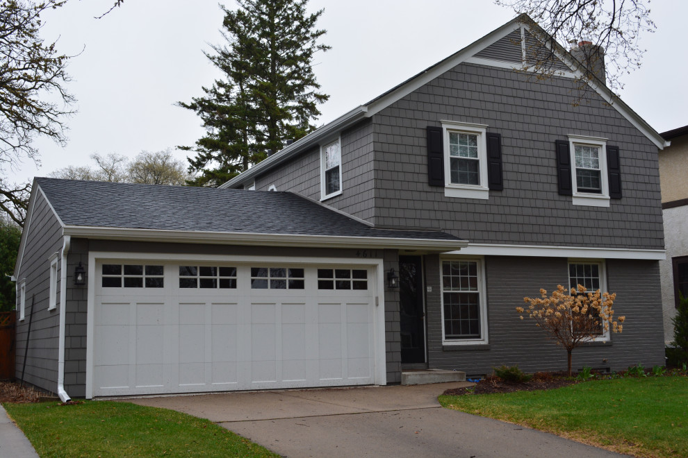 This is an example of a traditional grey house exterior in Minneapolis with concrete fiberboard siding, a gable roof, a shingle roof, a black roof and shingle siding.