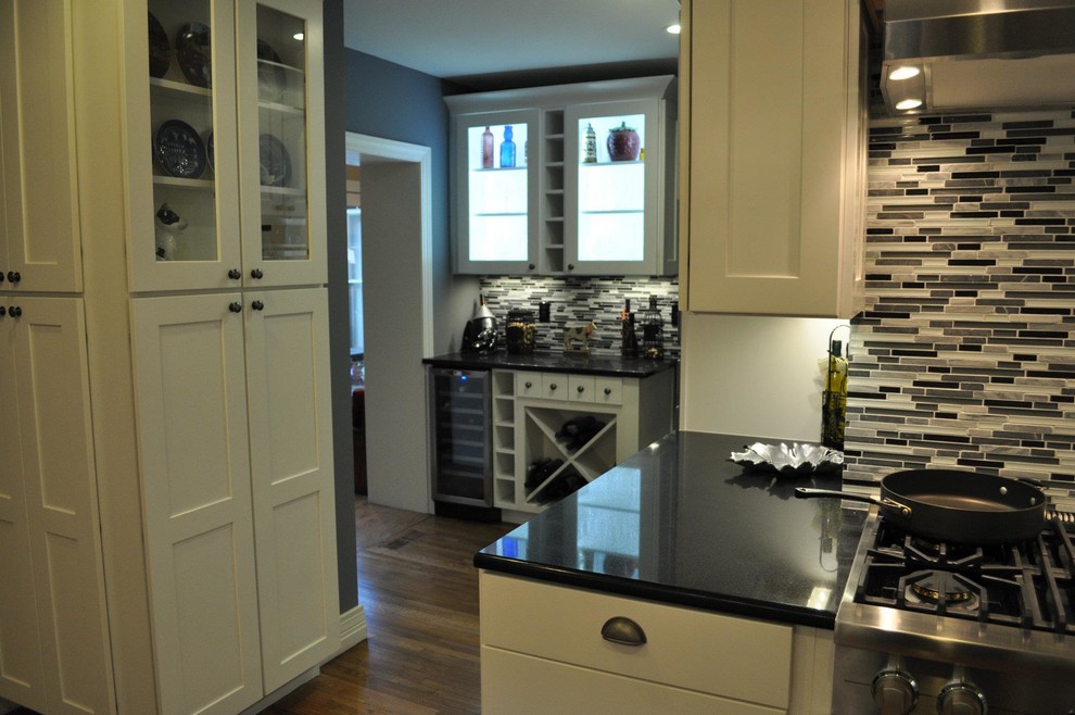 Inspiration for a transitional dark wood floor eat-in kitchen remodel with shaker cabinets, white cabinets, granite countertops, multicolored backsplash, glass tile backsplash and stainless steel appliances