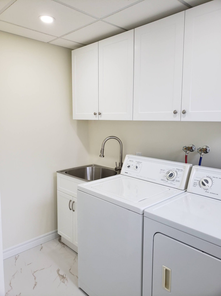 Transitional porcelain tile and white floor laundry room photo with an utility sink, shaker cabinets, white cabinets, white walls and a side-by-side washer/dryer