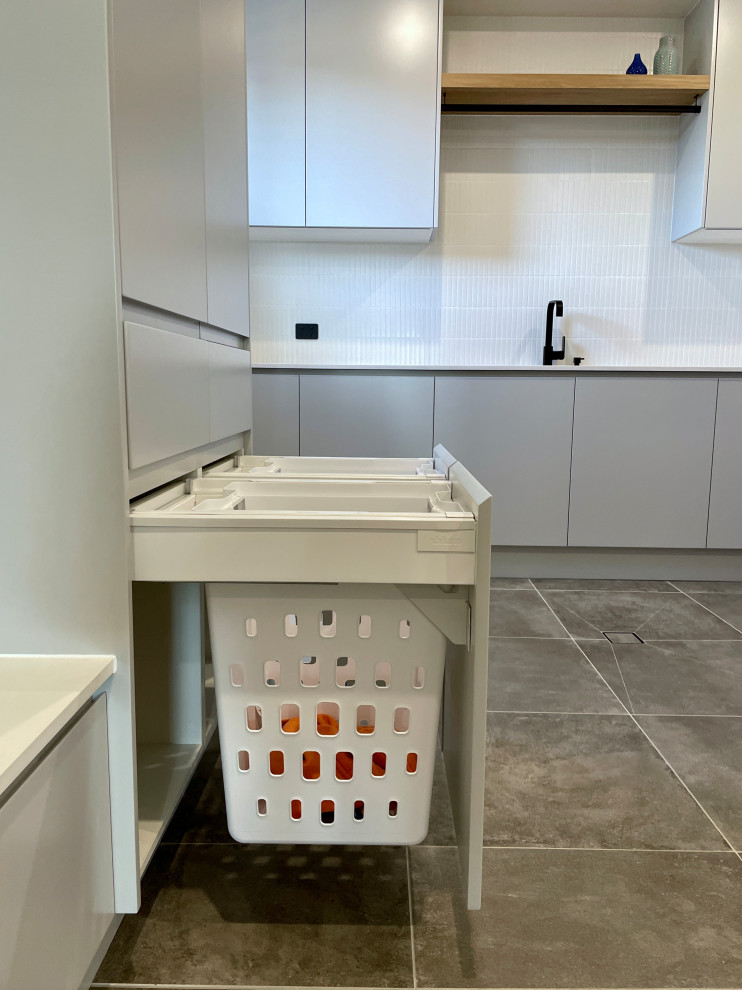 Inspiration for an expansive modern u-shaped dedicated laundry room in Sydney with an undermount sink, flat-panel cabinets, grey cabinets, quartz benchtops, white splashback, ceramic splashback, white walls, ceramic floors, a side-by-side washer and dryer, grey floor and white benchtop.
