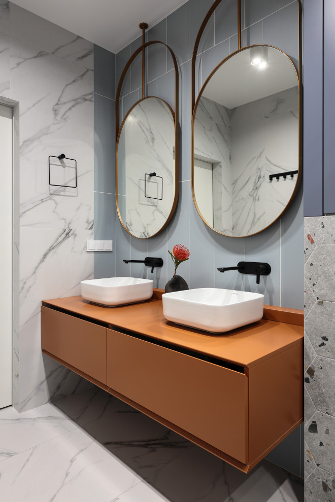 Стильный дизайн: ванная комната среднего размера в современном стиле с плоскими фасадами, оранжевыми фасадами, душем в нише, инсталляцией, синей плиткой, керамической плиткой, разноцветными стенами, полом из керамогранита, настольной раковиной, столешницей из искусственного камня, разноцветным полом, душем с раздвижными дверями, оранжевой столешницей, тумбой под две раковины и подвесной тумбой - последний тренд